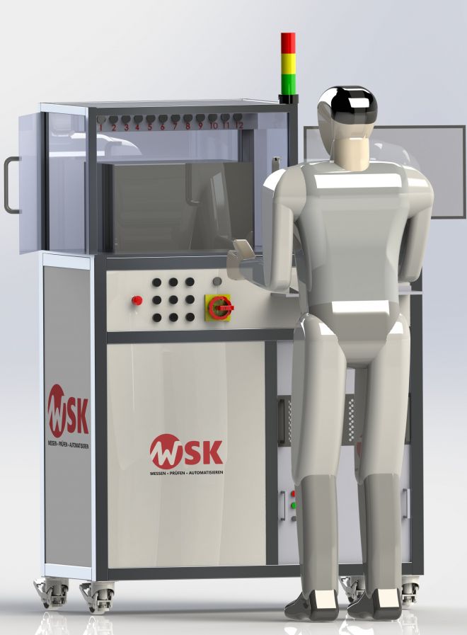 Frontansicht eines automatisierten Funktionstest- und Simulationsprüfstands von WSK mit Sicherheitsgehäuse, Bedienpanel, Not-Aus-Schalter und Signalleuchte. Ein Bediener steht direkt vor der Prüfzelle und interagiert mit dem System.
